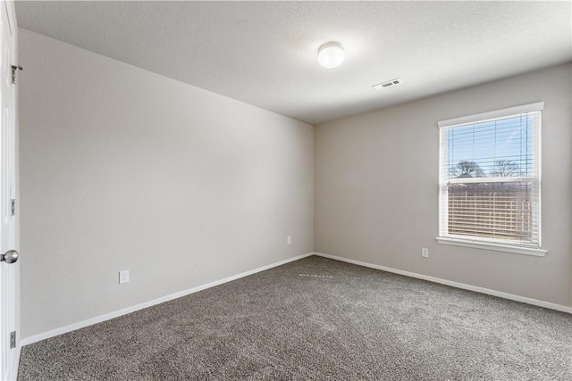 carpeted spare room featuring visible vents, a textured ceiling, and baseboards