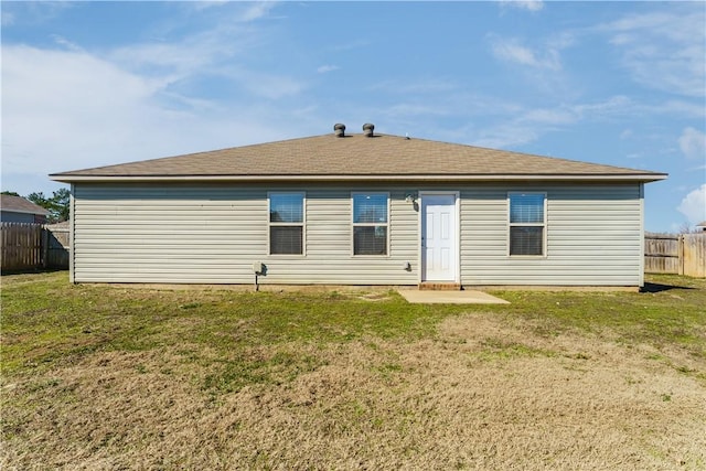 rear view of property featuring a patio area, fence, and a lawn