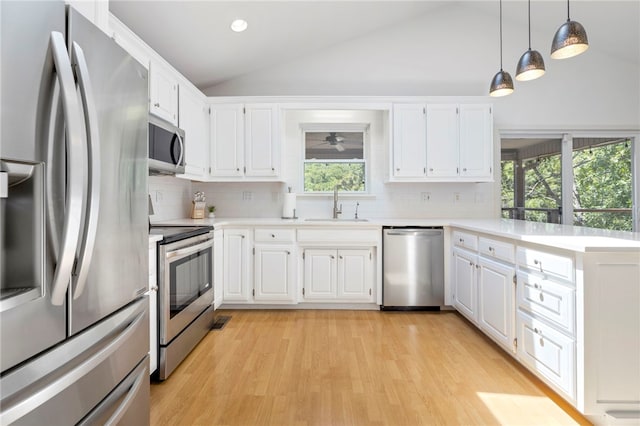 kitchen featuring light countertops, appliances with stainless steel finishes, vaulted ceiling, a sink, and a peninsula