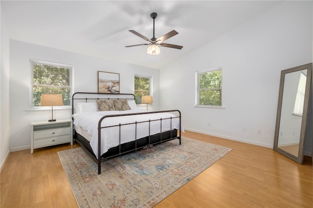 bedroom featuring light wood-type flooring, lofted ceiling, multiple windows, and baseboards