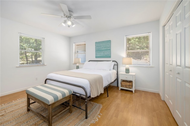 bedroom with baseboards, a closet, a ceiling fan, and light wood-style floors