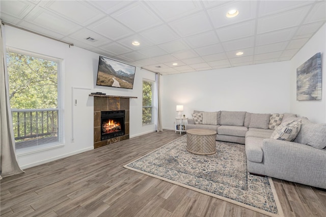 living area featuring plenty of natural light, a tiled fireplace, and wood finished floors