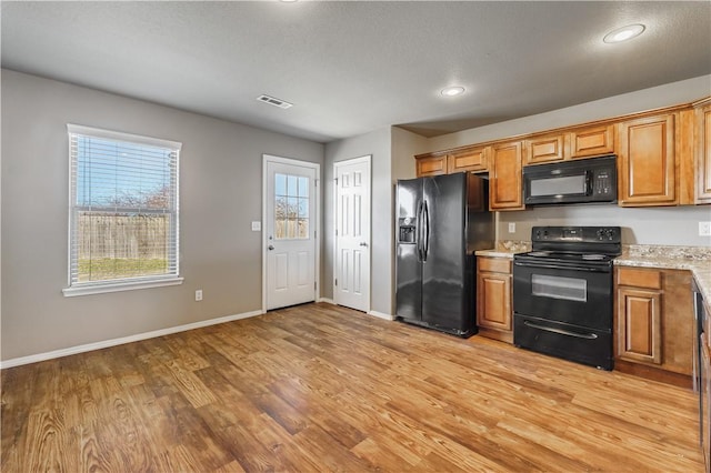 kitchen featuring black appliances, light wood-style flooring, visible vents, and brown cabinets