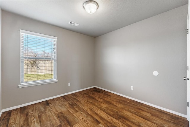 spare room with visible vents, baseboards, and wood finished floors