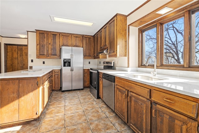 kitchen featuring light countertops, appliances with stainless steel finishes, a sink, a peninsula, and under cabinet range hood