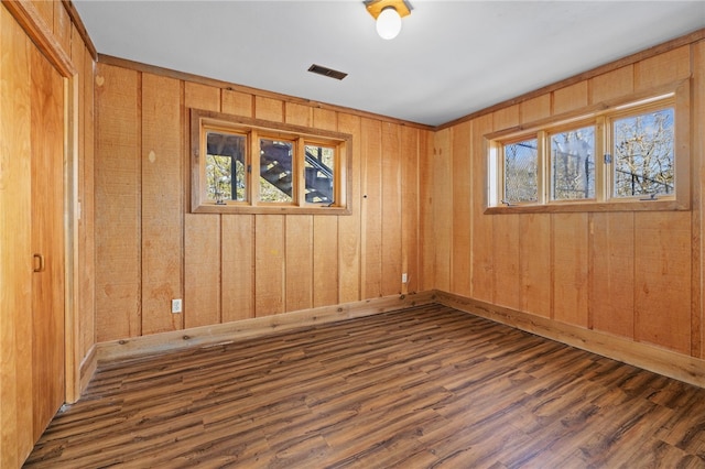 spare room with dark wood-style flooring, visible vents, baseboards, and a healthy amount of sunlight