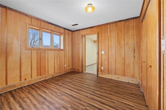 empty room with visible vents, wood walls, and wood finished floors