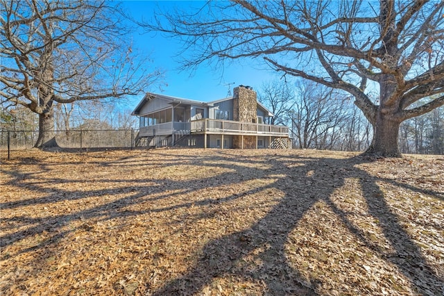 rear view of property featuring a chimney, fence, and a wooden deck