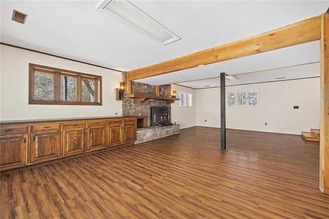 unfurnished living room featuring dark wood-style flooring, a fireplace, visible vents, and a healthy amount of sunlight