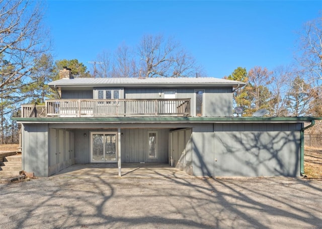 back of property featuring a deck, metal roof, and a chimney