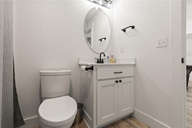 bathroom featuring baseboards, vanity, toilet, and wood finished floors