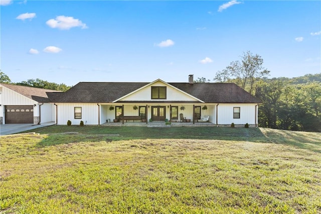 view of front of house with a chimney, a porch, a front lawn, and an attached garage