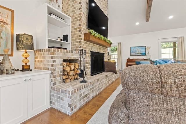 living area with light wood-style floors, recessed lighting, a brick fireplace, and vaulted ceiling