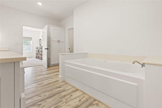 full bathroom with recessed lighting, wood finished floors, vanity, and a bath