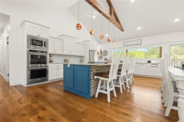 kitchen with a healthy amount of sunlight, appliances with stainless steel finishes, decorative backsplash, and dark wood-style flooring