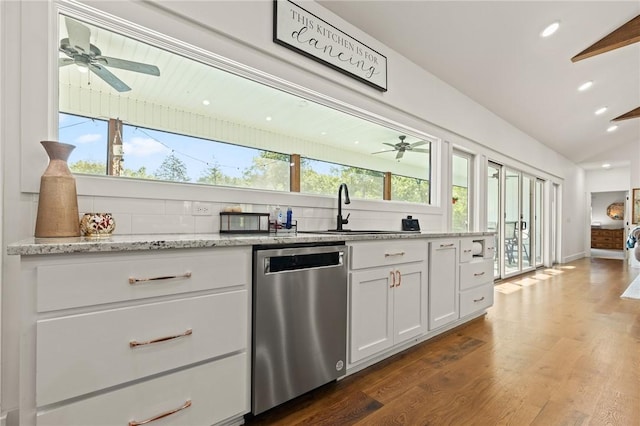 kitchen with decorative backsplash, lofted ceiling, stainless steel dishwasher, white cabinetry, and a sink