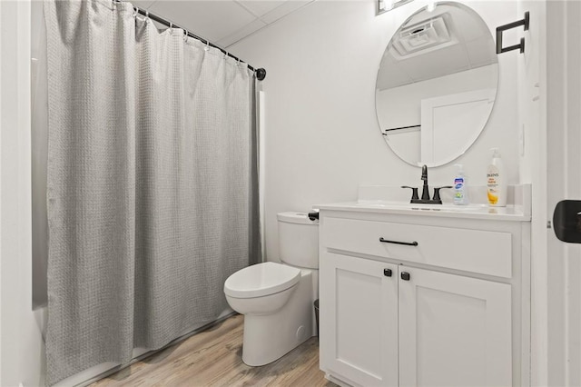 bathroom with vanity, a paneled ceiling, wood finished floors, and toilet