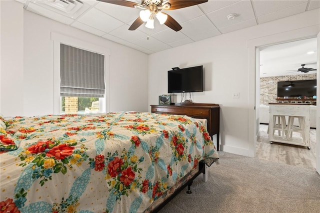 bedroom with a drop ceiling, carpet flooring, visible vents, a ceiling fan, and baseboards