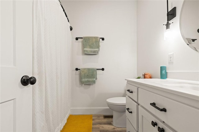 bathroom with visible vents, toilet, vanity, wood finished floors, and baseboards