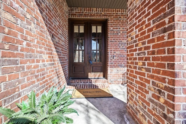 property entrance featuring french doors and brick siding