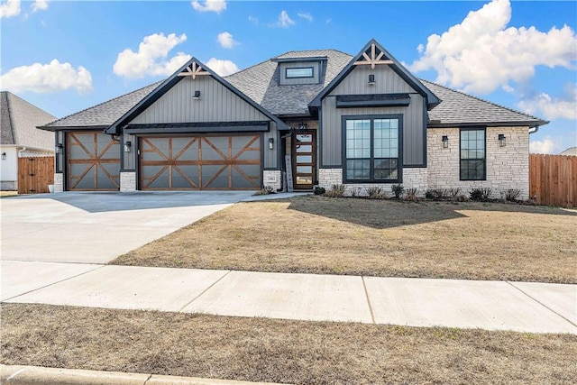 view of front facade with driveway, roof with shingles, an attached garage, fence, and a front yard