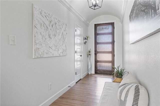 foyer with an inviting chandelier, vaulted ceiling, baseboards, and wood finished floors