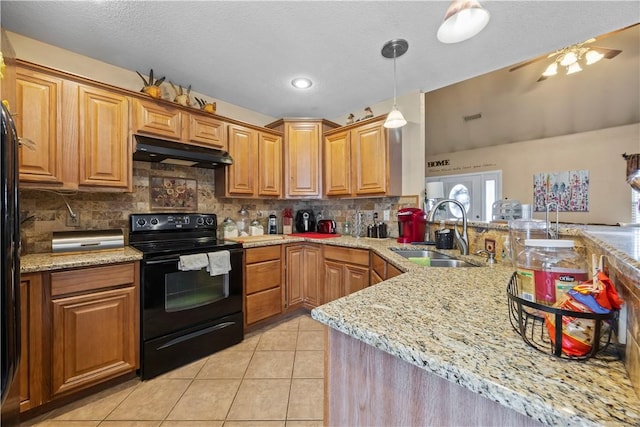 kitchen with light tile patterned floors, decorative backsplash, black electric range oven, under cabinet range hood, and a sink