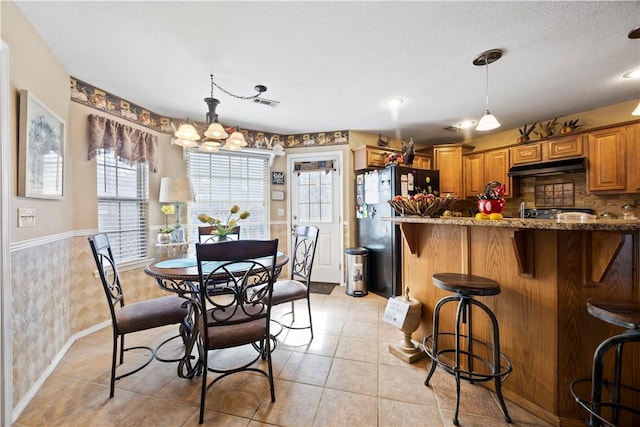 dining area featuring wainscoting, visible vents, a textured ceiling, and light tile patterned floors