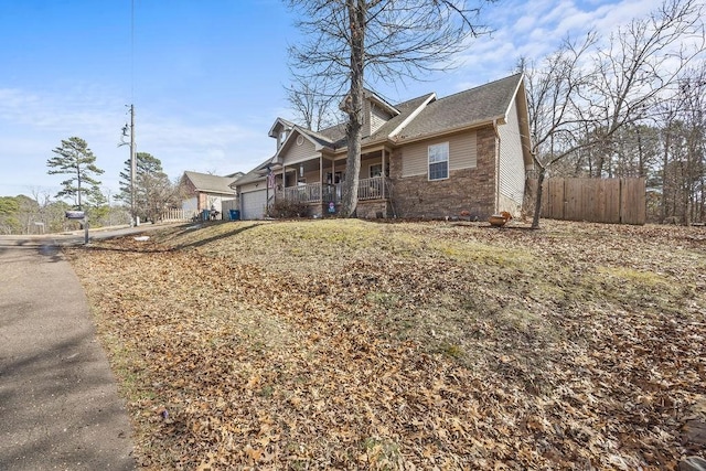 view of front of home featuring a garage, covered porch, and fence