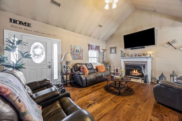 living room with high vaulted ceiling, a lit fireplace, visible vents, and wood finished floors