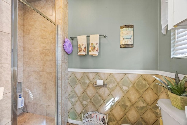 bathroom with toilet, a shower stall, and tile walls