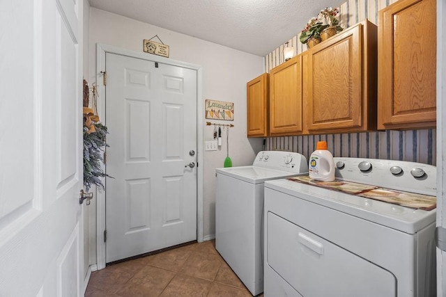 clothes washing area with a textured ceiling, separate washer and dryer, tile patterned flooring, and cabinet space