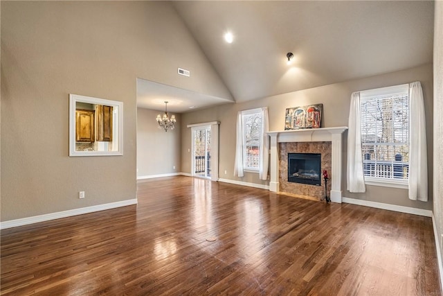 unfurnished living room featuring visible vents, a notable chandelier, a premium fireplace, and wood finished floors