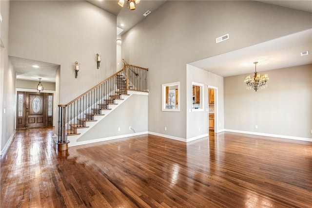 unfurnished living room featuring stairs, baseboards, wood finished floors, and a notable chandelier