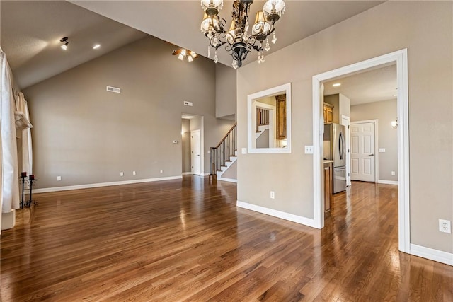 interior space featuring wood finished floors, visible vents, baseboards, stairs, and an inviting chandelier