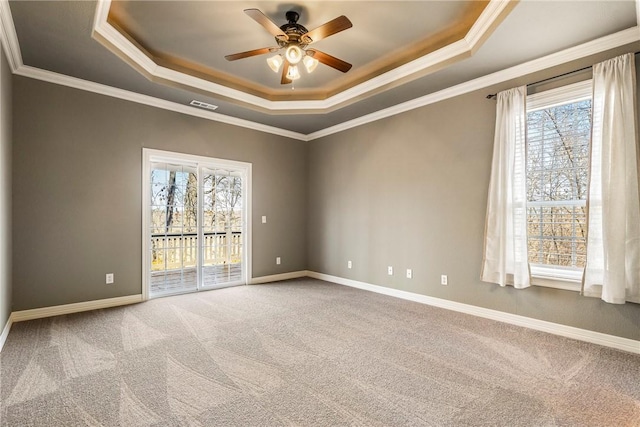 empty room with crown molding, a tray ceiling, carpet, and baseboards