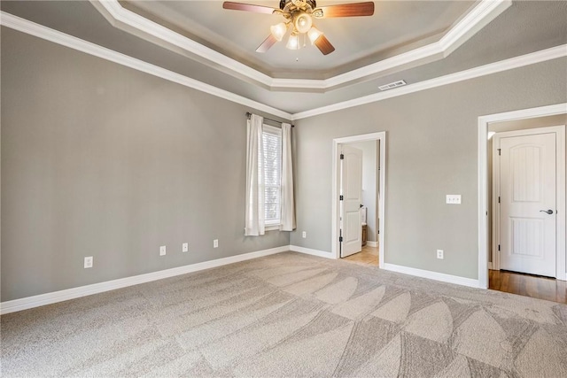 unfurnished bedroom featuring carpet floors, crown molding, a raised ceiling, visible vents, and baseboards