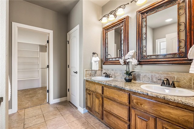 bathroom with double vanity, tile patterned flooring, baseboards, and a sink