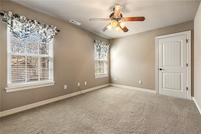 empty room featuring ceiling fan, carpet, visible vents, and baseboards