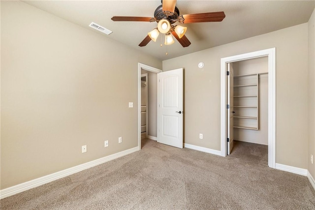 unfurnished bedroom featuring carpet, a walk in closet, visible vents, and baseboards