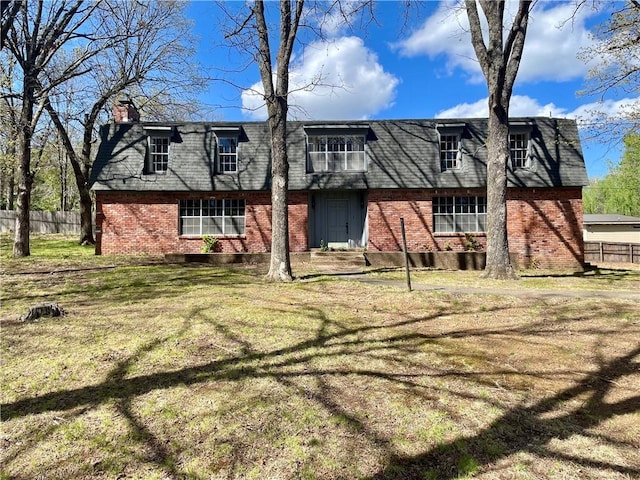 back of property featuring brick siding, fence, roof with shingles, a lawn, and a chimney