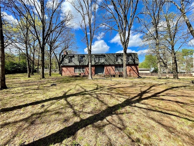 view of front of property featuring brick siding, fence, and a front lawn