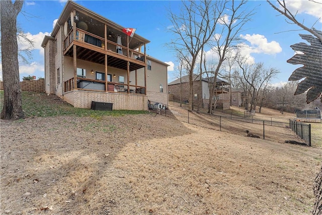 rear view of property with a balcony and a fenced backyard