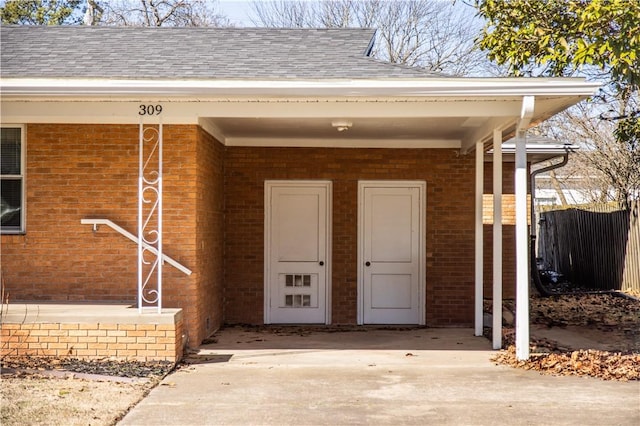 property entrance featuring brick siding and roof with shingles