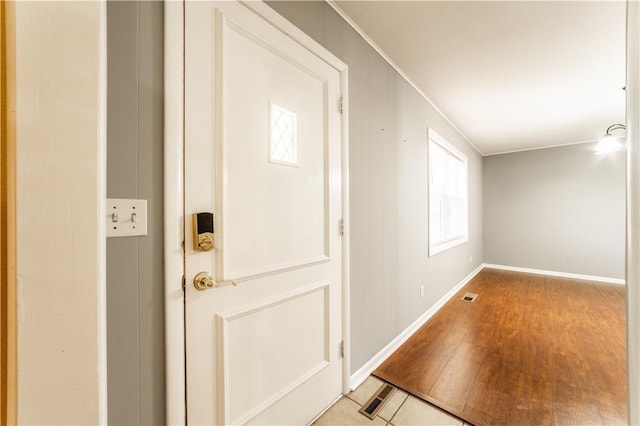 foyer featuring crown molding, light wood finished floors, visible vents, and baseboards