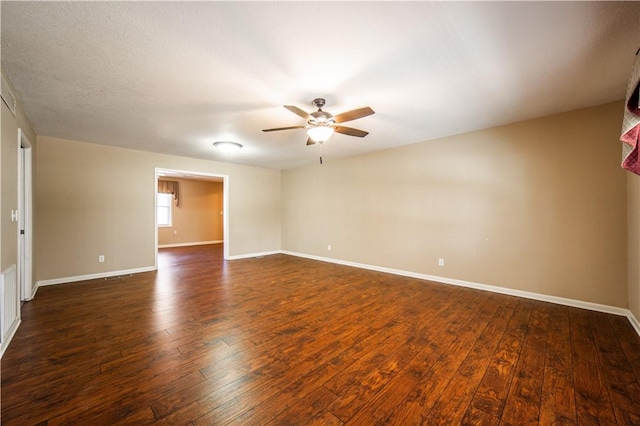 spare room featuring dark wood-style floors, ceiling fan, and baseboards