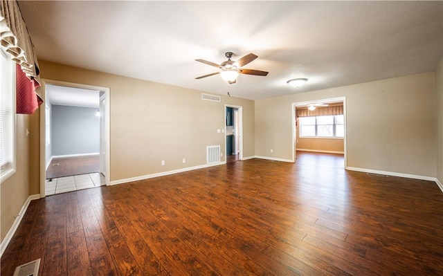 spare room featuring ceiling fan, dark wood-style flooring, and visible vents