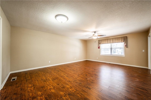 unfurnished room featuring a ceiling fan, dark wood-style flooring, visible vents, and baseboards