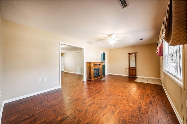 unfurnished living room with visible vents, a glass covered fireplace, hardwood / wood-style flooring, and baseboards