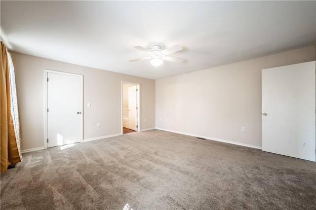 carpeted spare room featuring a ceiling fan and baseboards